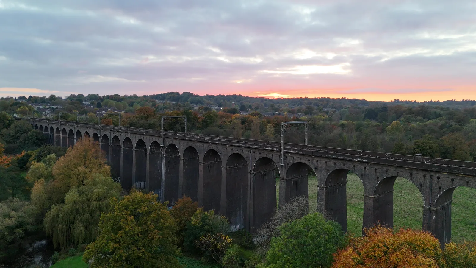 Digswell Viaduct near Welwyn Garden City at sunset, its brick arches crossing a valley of autumn trees.