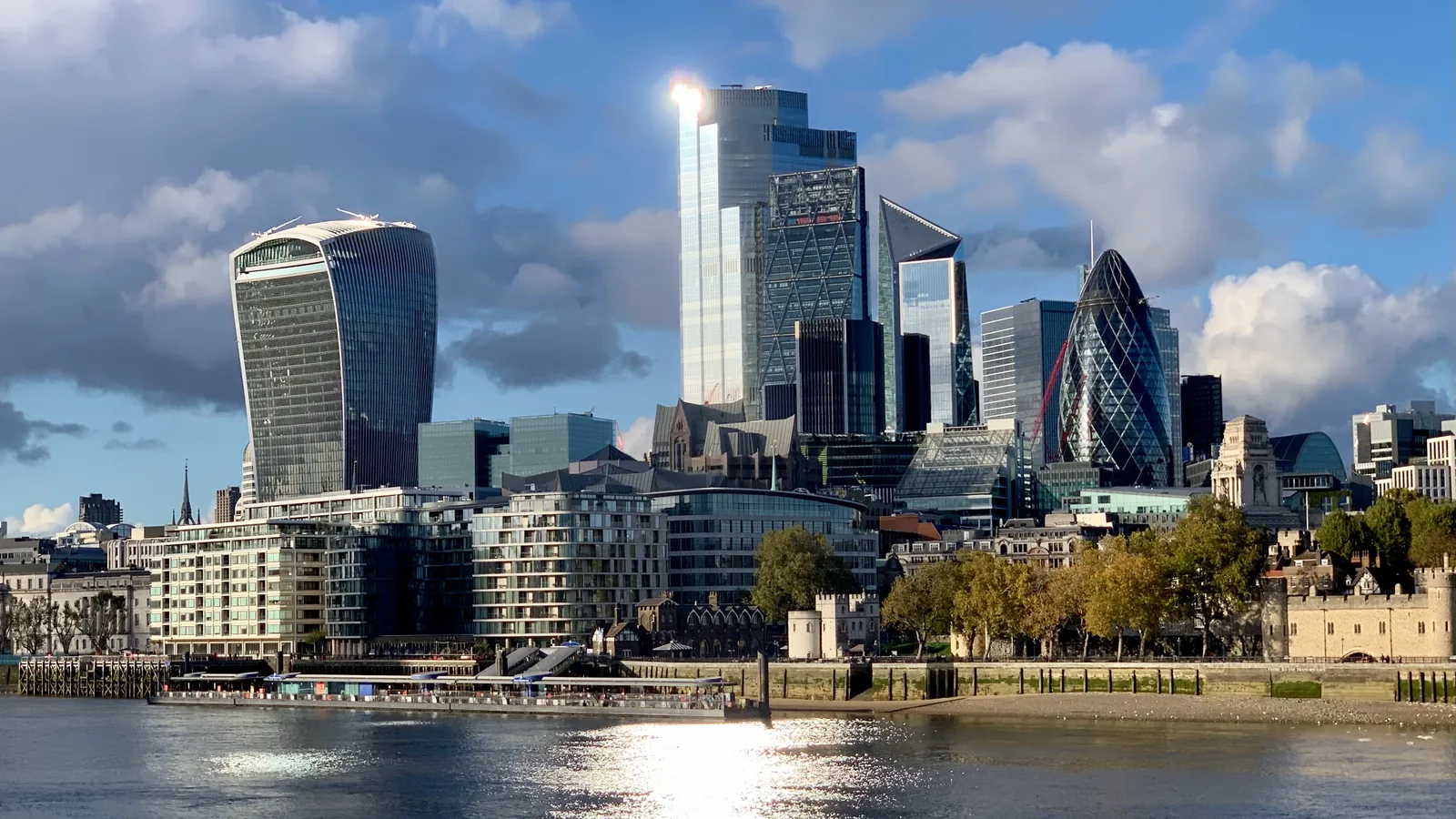 The City of London's towers, including the Walkie Talkie and the Gherkin, above the Thames, with the Tower of London on the right.